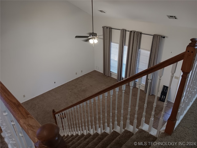 stairs featuring lofted ceiling, ceiling fan, and carpet floors