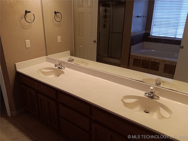 bathroom with vanity, a relaxing tiled tub, and tile patterned flooring