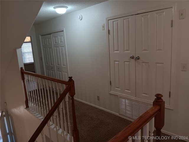 hall with a textured ceiling and carpet flooring