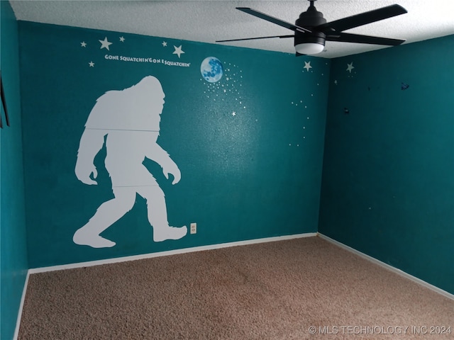 carpeted spare room featuring ceiling fan and a textured ceiling