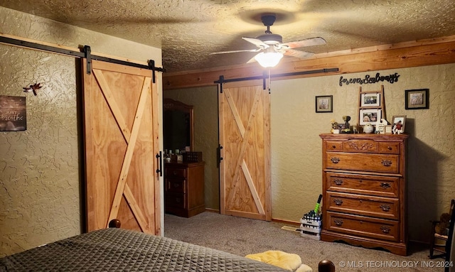 bedroom featuring carpet, ceiling fan, a barn door, and a textured ceiling