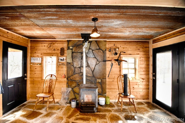 foyer entrance with a wood stove, wood walls, and wood ceiling