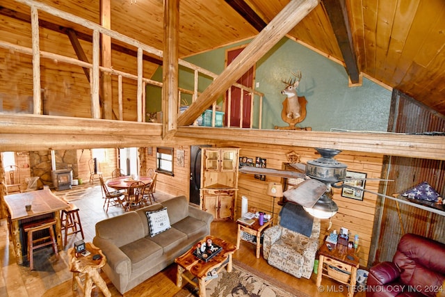 living room with wooden walls, wood-type flooring, beam ceiling, wooden ceiling, and a wood stove