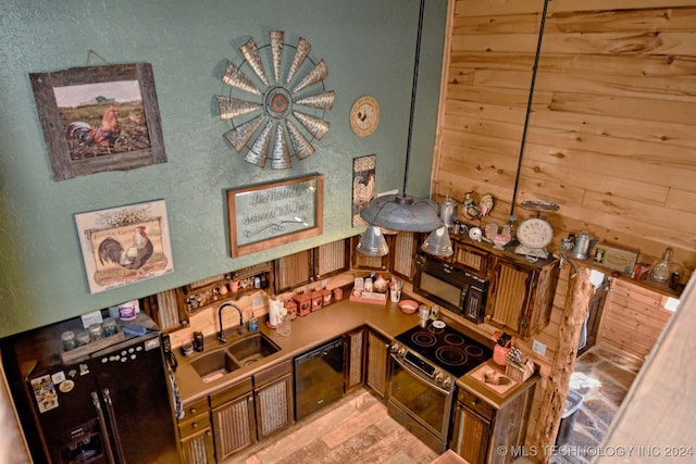 kitchen with black appliances, sink, and wooden walls