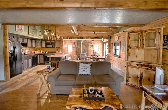 living room featuring beam ceiling, light wood-type flooring, and wooden walls