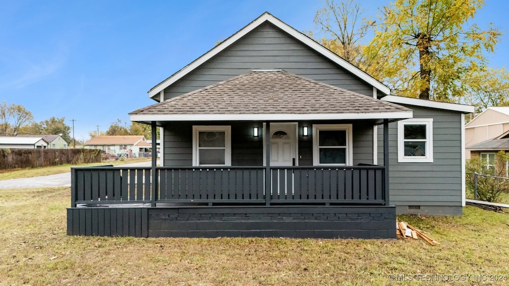 back of property featuring covered porch and a yard