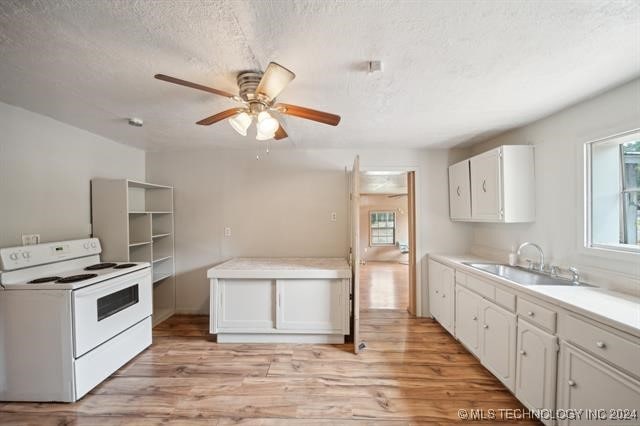 kitchen featuring white range with electric cooktop, light hardwood / wood-style flooring, and white cabinets