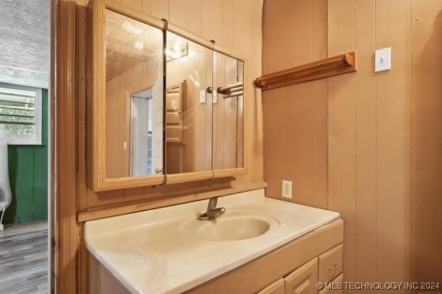 bathroom featuring wood walls, vanity, and wood-type flooring