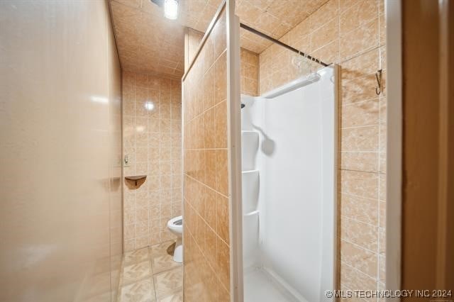 bathroom with toilet and tiled shower