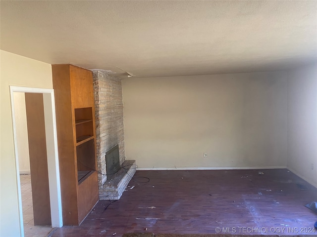 unfurnished living room with dark hardwood / wood-style flooring, a textured ceiling, and a fireplace