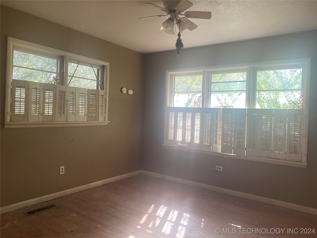 spare room featuring ceiling fan, hardwood / wood-style flooring, and a healthy amount of sunlight