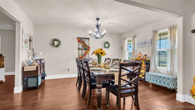 dining space featuring dark wood-type flooring and a notable chandelier