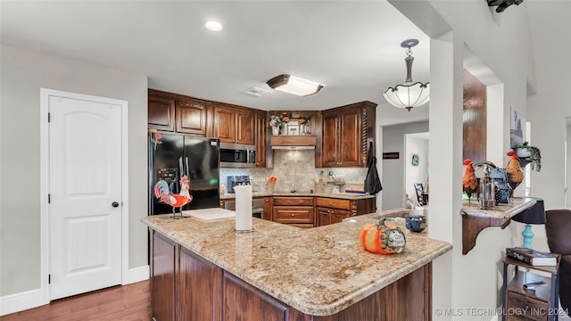 kitchen with light stone counters, kitchen peninsula, hardwood / wood-style flooring, decorative backsplash, and black appliances