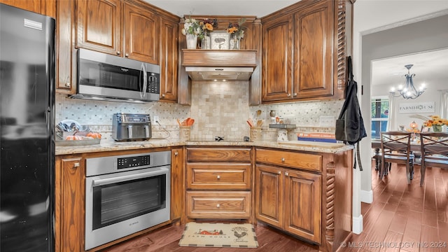 kitchen with black appliances, dark hardwood / wood-style flooring, a notable chandelier, light stone countertops, and backsplash