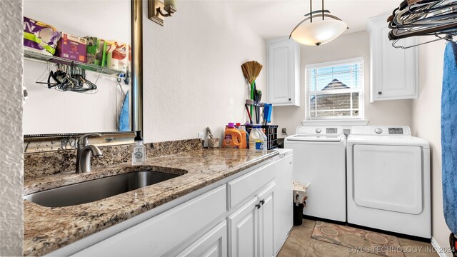 clothes washing area featuring cabinets, washing machine and dryer, sink, and light tile patterned floors