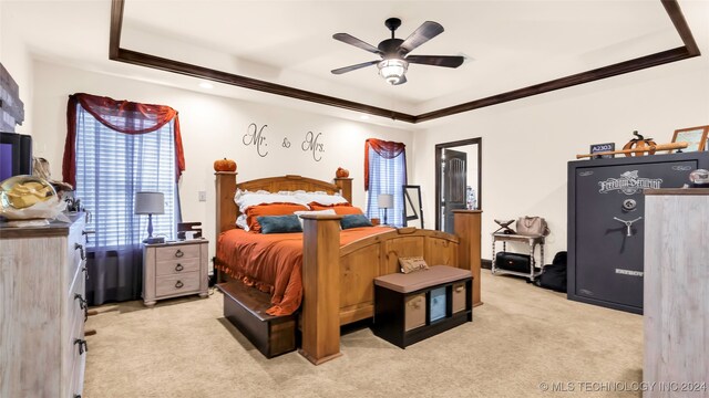 bedroom with ceiling fan, light colored carpet, a tray ceiling, and crown molding