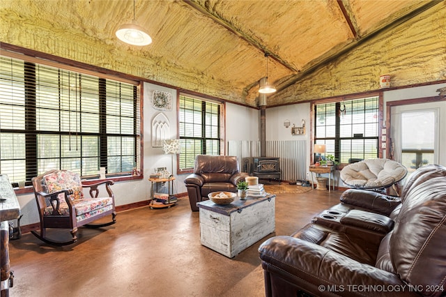 living room featuring a wood stove, plenty of natural light, lofted ceiling, and concrete floors