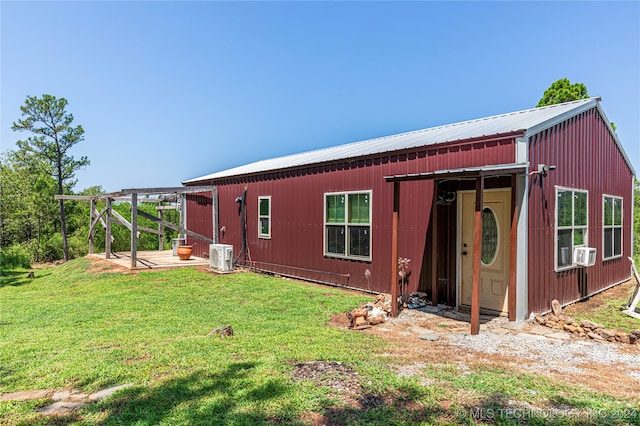 rear view of property featuring cooling unit and a lawn