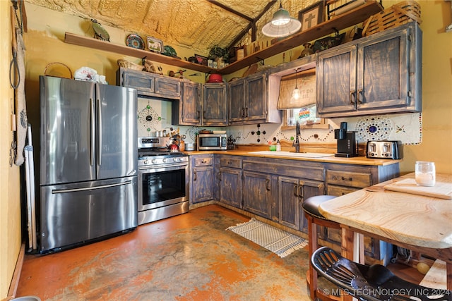 kitchen with dark brown cabinetry, lofted ceiling, sink, and appliances with stainless steel finishes