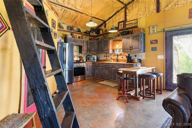 kitchen featuring concrete flooring, appliances with stainless steel finishes, vaulted ceiling, and dark brown cabinets