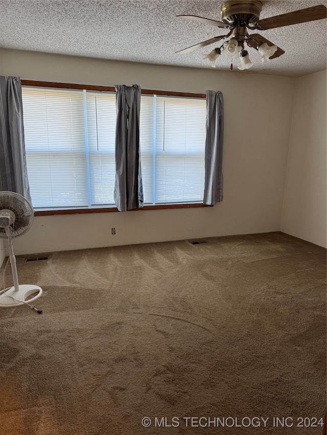 spare room featuring ceiling fan, carpet, and a textured ceiling