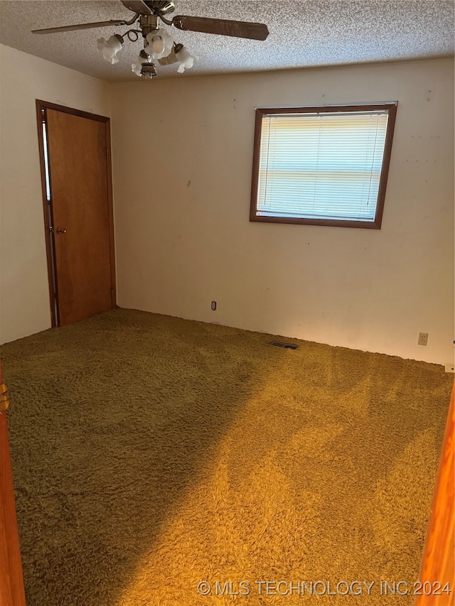 carpeted empty room featuring a textured ceiling and ceiling fan