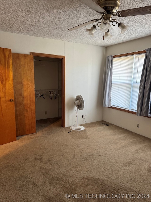 unfurnished bedroom featuring ceiling fan, a closet, carpet, and a textured ceiling