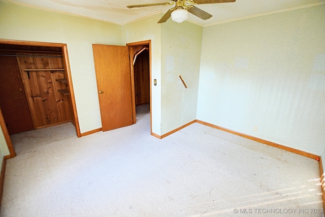 unfurnished bedroom with a closet, light carpet, ceiling fan, and crown molding