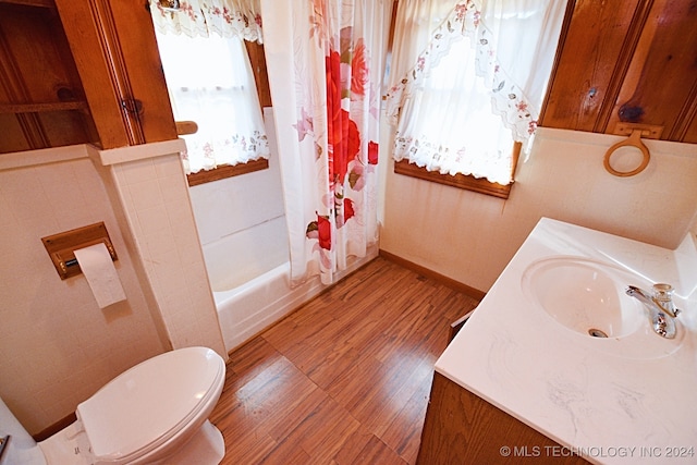 full bathroom with toilet, tile walls, hardwood / wood-style flooring, vanity, and shower / tub combo with curtain