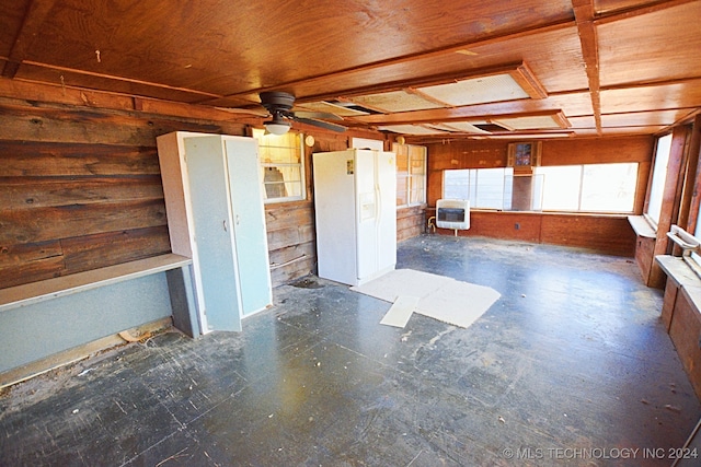 spare room featuring wood walls, ceiling fan, and heating unit