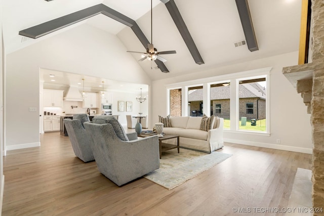 living room with a stone fireplace, light wood-type flooring, beam ceiling, high vaulted ceiling, and ceiling fan with notable chandelier