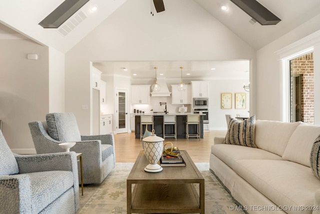 living room featuring ceiling fan, sink, light wood-type flooring, and high vaulted ceiling