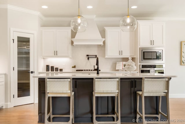 kitchen featuring white cabinets, stainless steel appliances, and a center island with sink