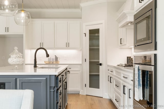 kitchen with white cabinetry, sink, appliances with stainless steel finishes, ornamental molding, and pendant lighting