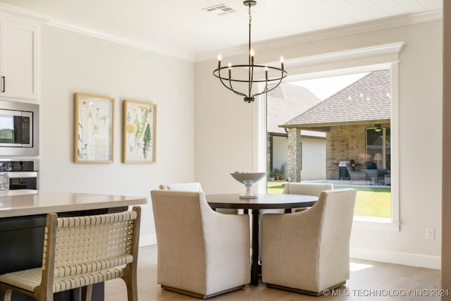 dining area featuring ornamental molding, light hardwood / wood-style flooring, and a chandelier