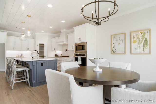 dining space featuring ornamental molding, sink, a notable chandelier, and light hardwood / wood-style floors