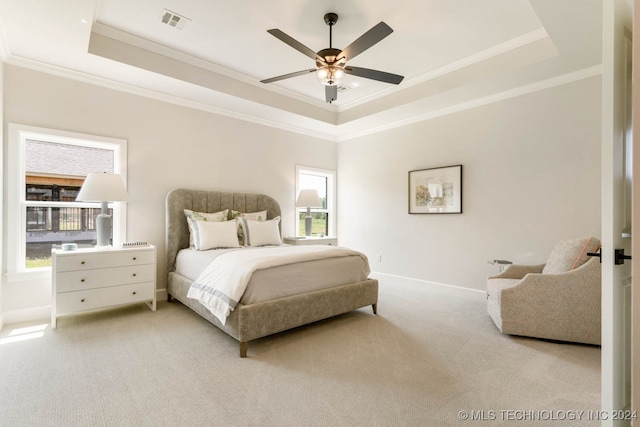 carpeted bedroom featuring a tray ceiling, ceiling fan, and crown molding