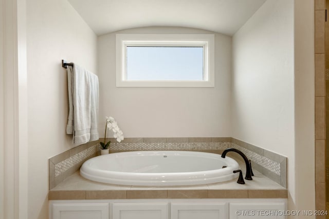 bathroom with lofted ceiling and a tub