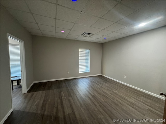 spare room featuring a drop ceiling and dark wood-type flooring