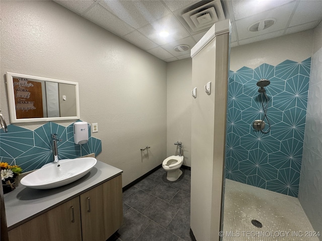 bathroom featuring a paneled ceiling, vanity, tile patterned flooring, toilet, and a shower