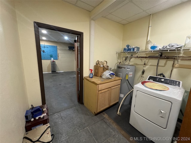 laundry room featuring water heater, washer / clothes dryer, and dark tile patterned floors