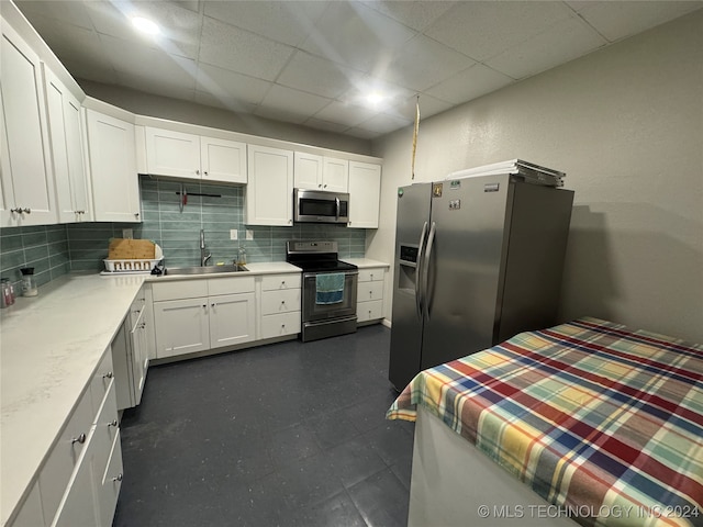 kitchen featuring tasteful backsplash, a paneled ceiling, appliances with stainless steel finishes, sink, and white cabinets