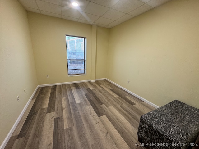 empty room with a drop ceiling and hardwood / wood-style flooring