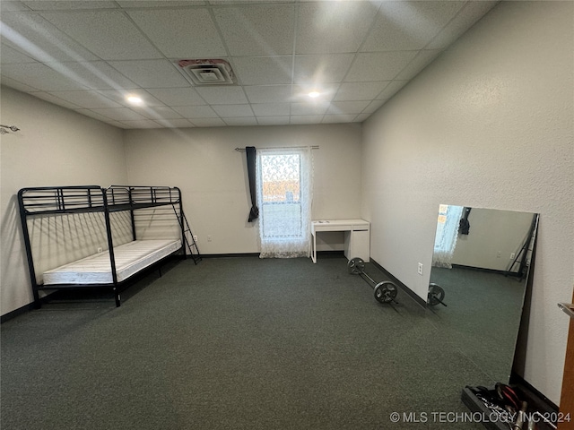 unfurnished bedroom with a drop ceiling and dark colored carpet