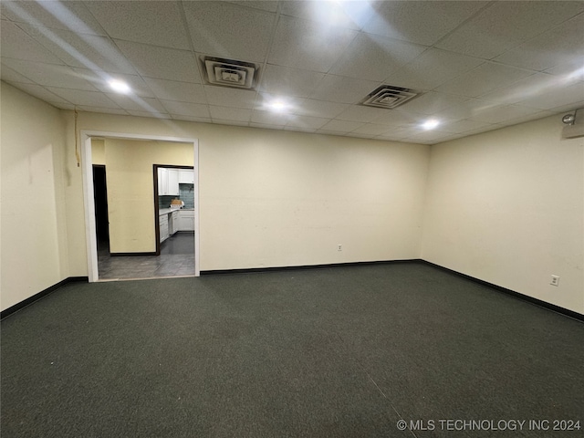 spare room with a paneled ceiling and dark carpet