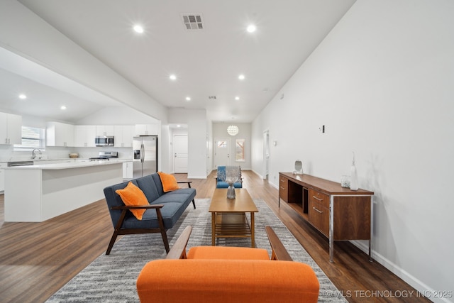 living room with vaulted ceiling, dark hardwood / wood-style floors, and sink