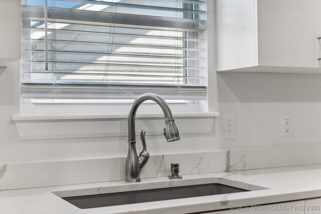 details with light stone countertops, sink, and white cabinets