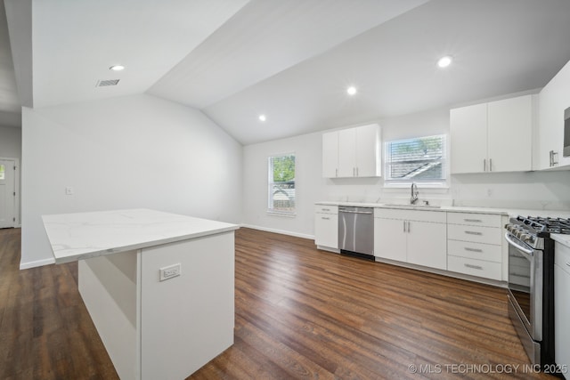 kitchen with sink, vaulted ceiling, appliances with stainless steel finishes, a kitchen island, and white cabinets