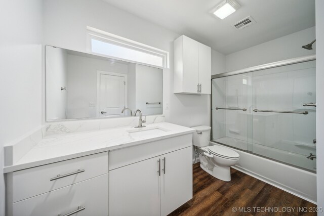 full bathroom with toilet, vanity, combined bath / shower with glass door, and hardwood / wood-style floors