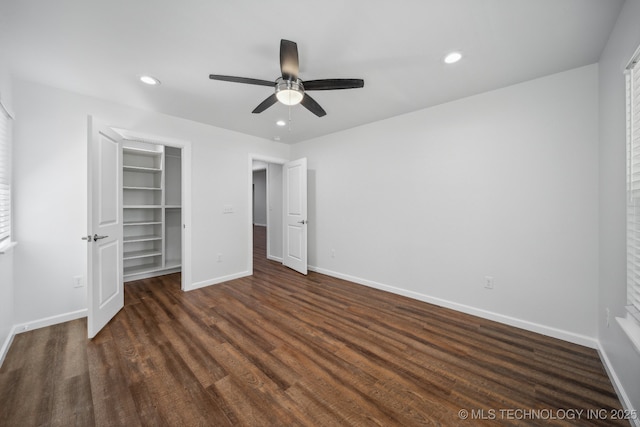 unfurnished bedroom featuring a closet, a walk in closet, dark hardwood / wood-style floors, and ceiling fan